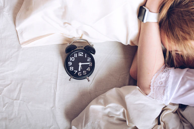 girl in bed with alarm clock, watch on