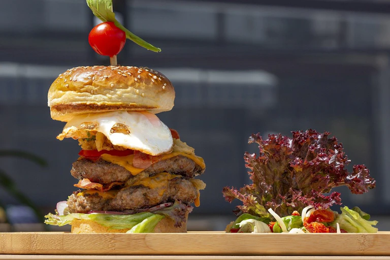 A large hamburger next to a small salad
