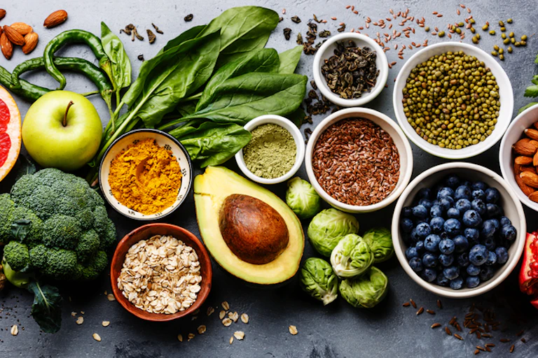 A colourful selection of food including fruits, vegetables, seeds and cereal.