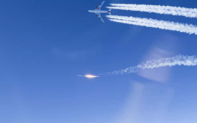 A rocket and a plane next to each other in the sky.