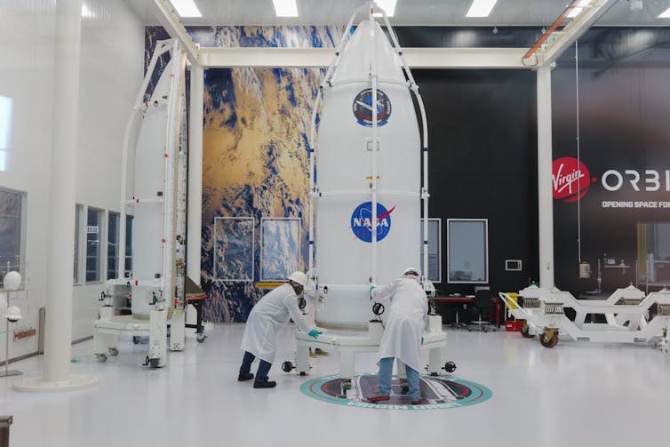 The NASA payload in a warehouse being inspected by two men.