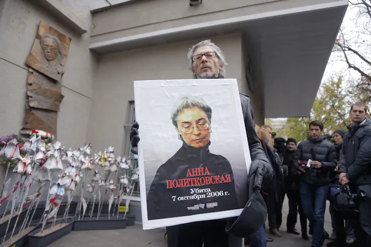 A man holds up a poster with a picture of Russian journalist Anna Politkovskaya, who was murdered in 2006.