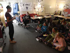 A grade school girl reads a poem to her class.