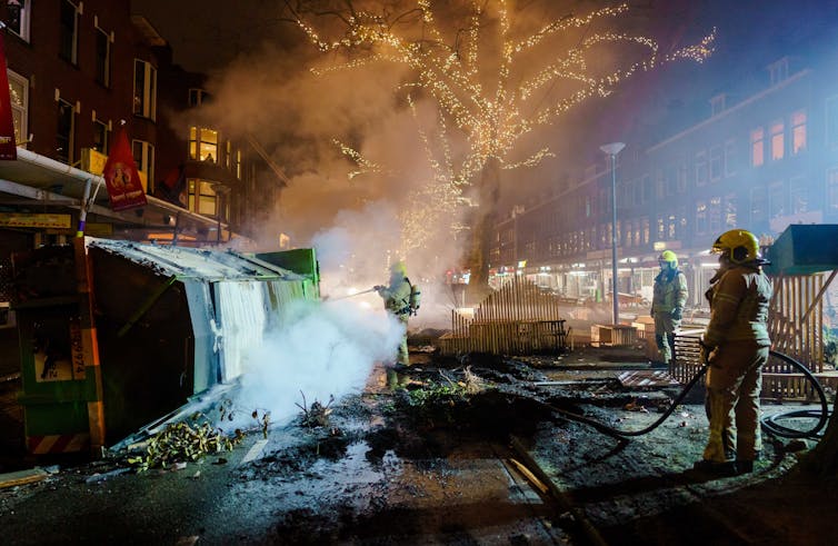 Firefighters extinguishing a fire on a damaged street.