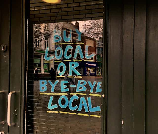 A storefront with a sign that reads Buy Local or Bye-Bye Local.