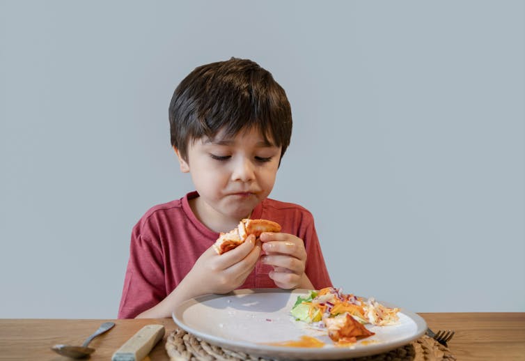 School-aged child eating salmon.