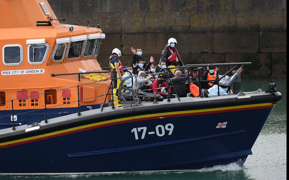 People waving at camera on border force boat with face masks on
