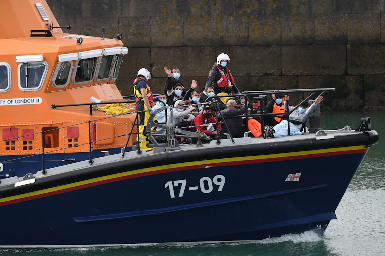 People waving at camera on border force boat with face masks on