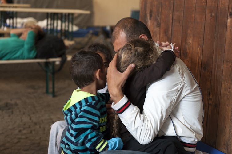 Man hugging three small children at asylum centre