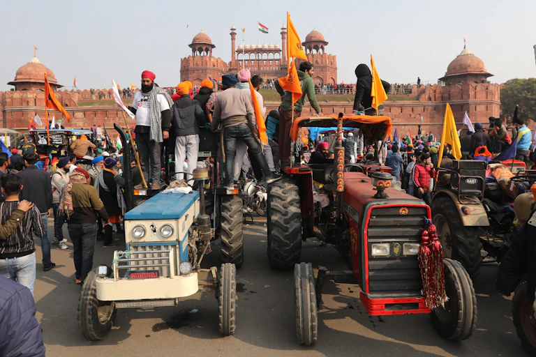 Men with flags stand on two tractors overlooking Delhi's Red Fort
