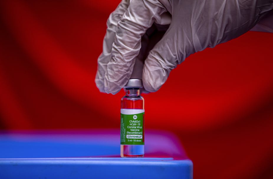 A vial of vaccine being picked up by a gloved hand