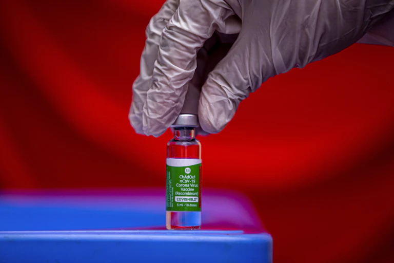 A vial of vaccine being picked up by a gloved hand