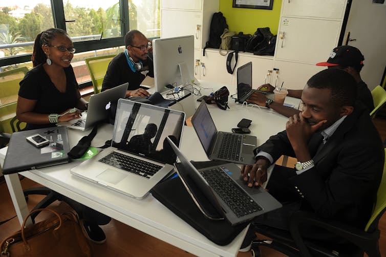 Four young Kenyans sit at a table with computers