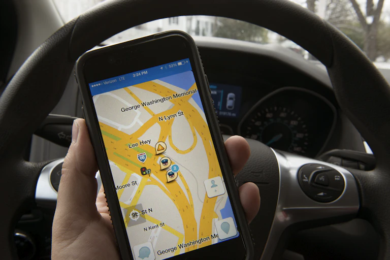 A hand holds an iPhone displaying the Waze traffic app.