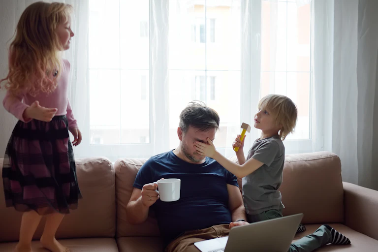Kids play around a father on a couch.