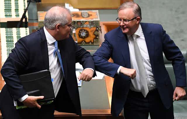 Scott Morrison and Anthony Albanese nudge elbows together in parliament.
