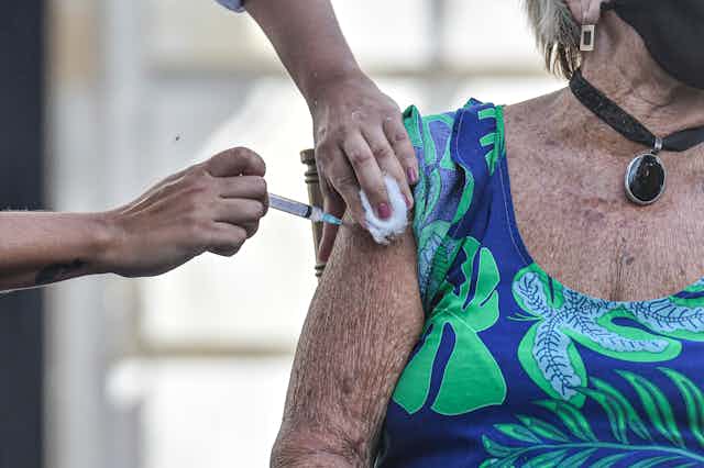 An elderly woman receives the vaccine in Brazil.