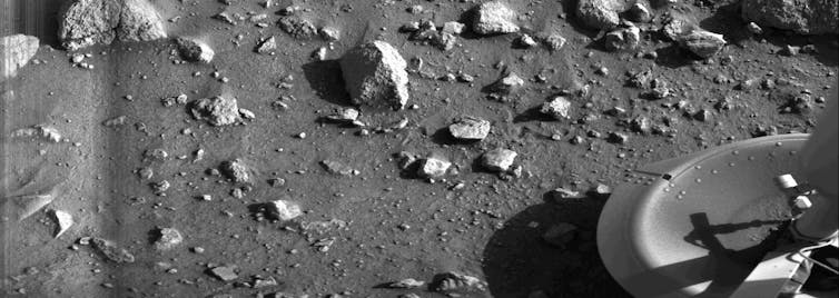 A rock strewn field and the foot of the Viking 1 lander appears in one corner.