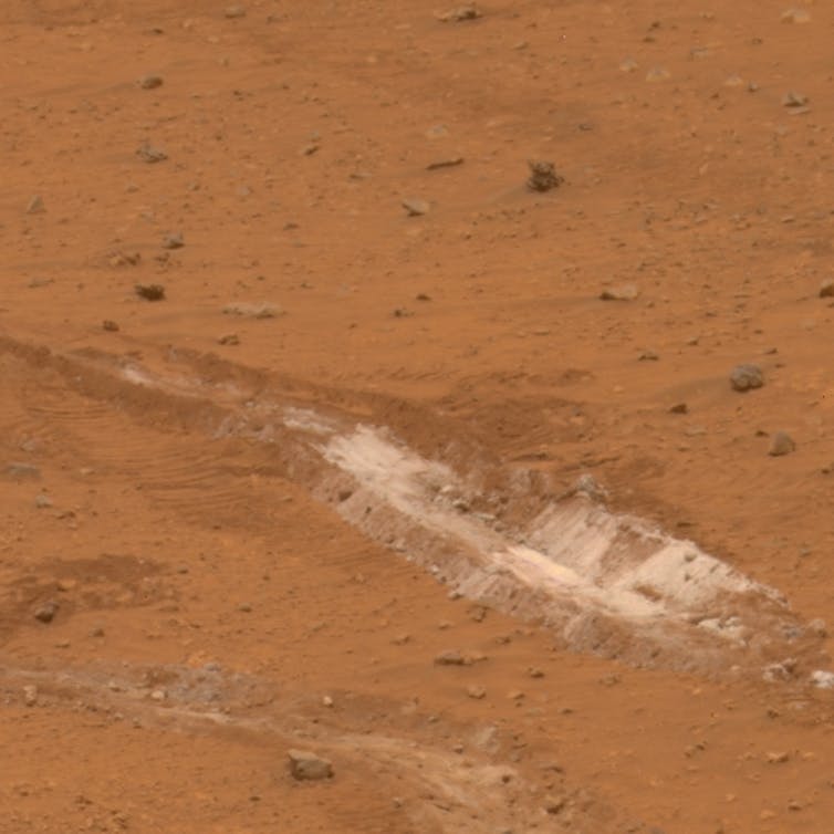 Track of disturbed red soil revealing white silica.