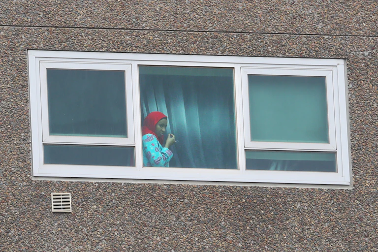Young lady looking out the window of an apartment in a public housing tower in Flemington, Melbourne.