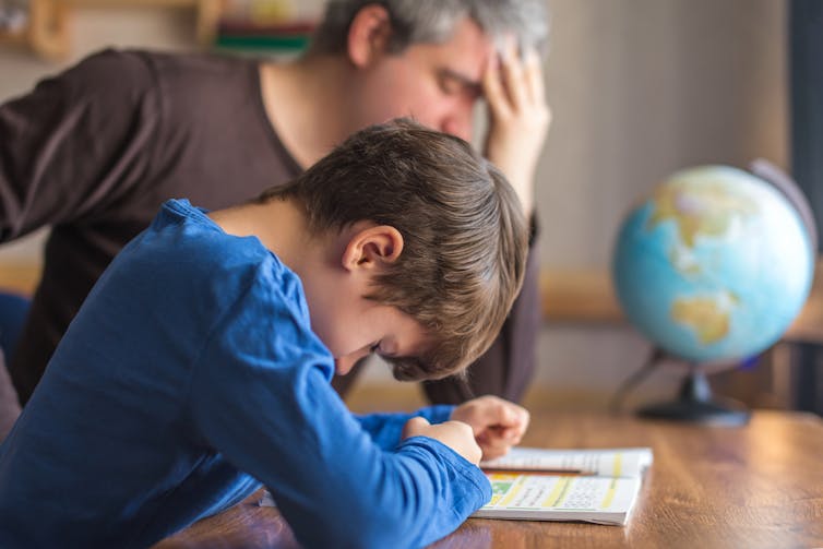 Father and son looking stressed doing homework