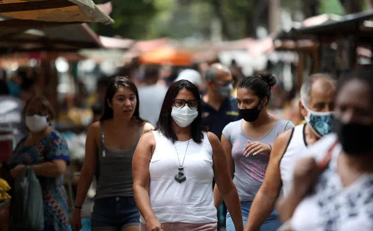 A woman in a mask walking down a street in Rio de Janeiro, Brazil