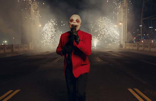 His face covered in bandages, The Weeknd sings as fireworks explode behind him.