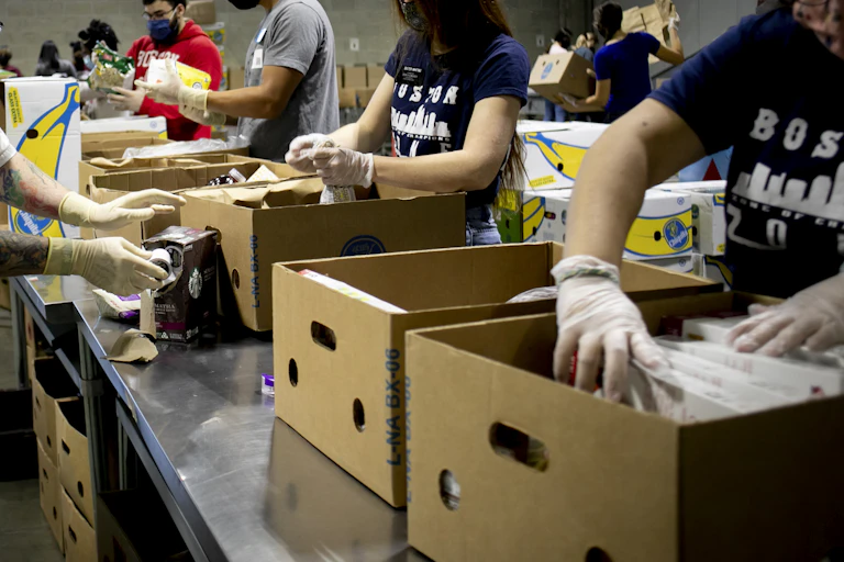 People load food into cardboard cartons