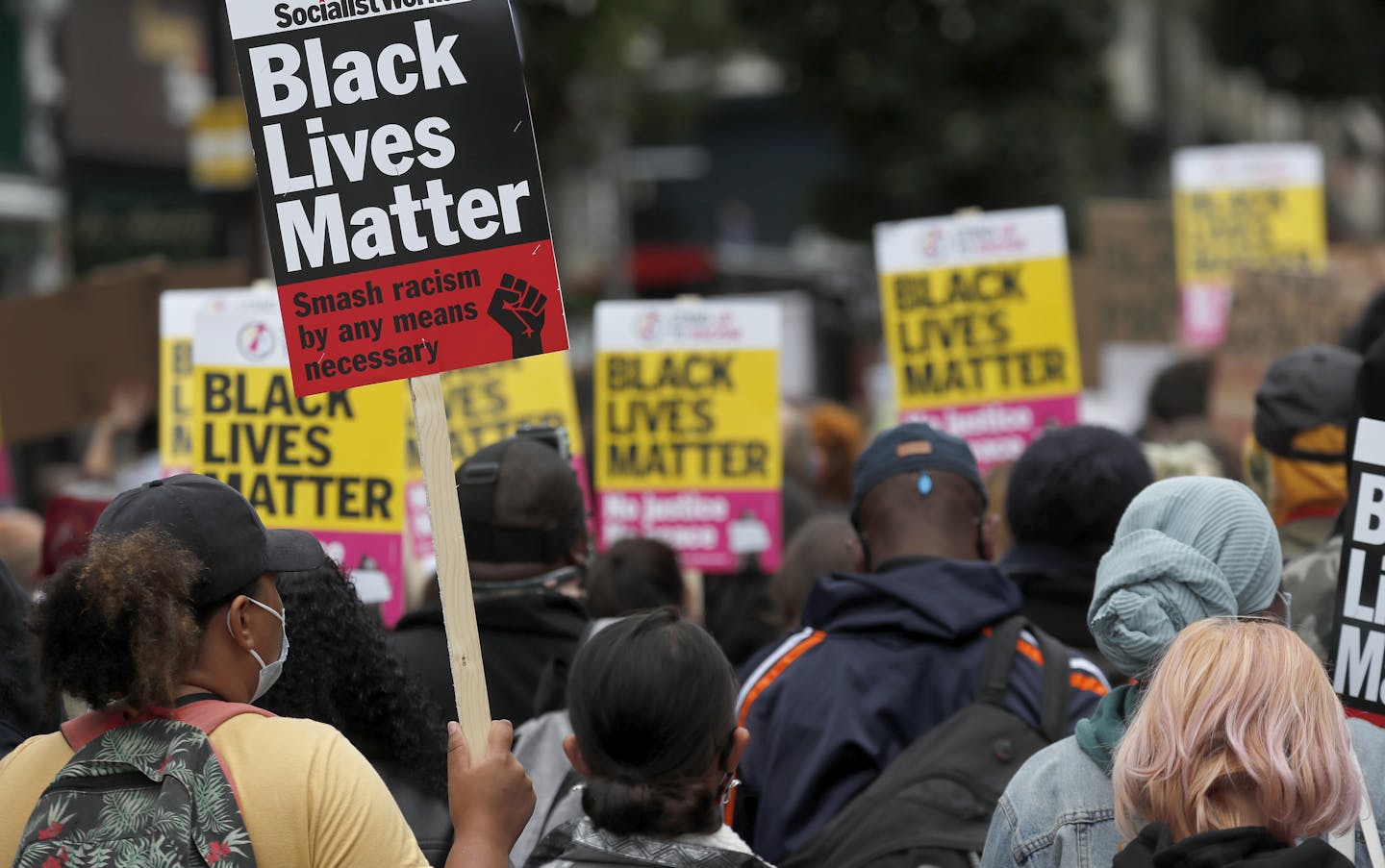 Black Lives Matter protesters hold up posters. One reads 'Smash racism by any means necessary.'