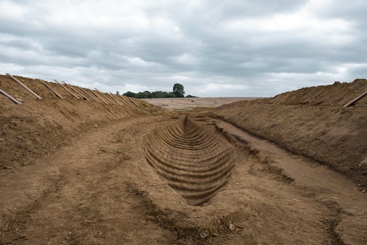 Wide trench containing the imprint of a wooden ship in the soil.