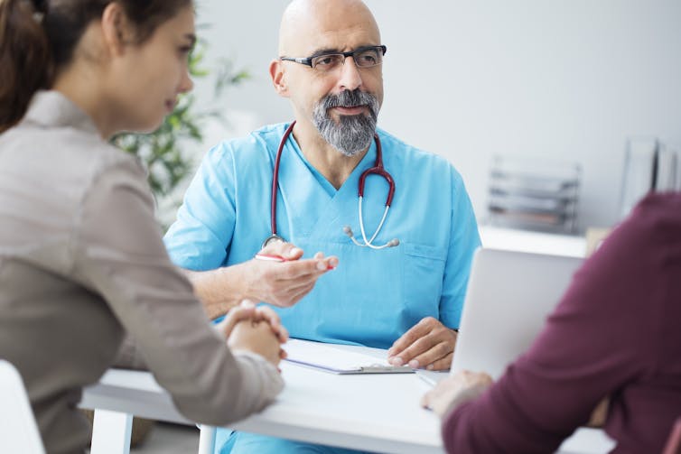 A doctor talks to a couple.