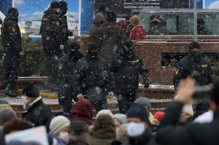 Police wearing face coverings approach a group of protesters.