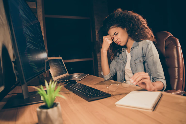 Young woman sitting in front of her computer looking frustrated.