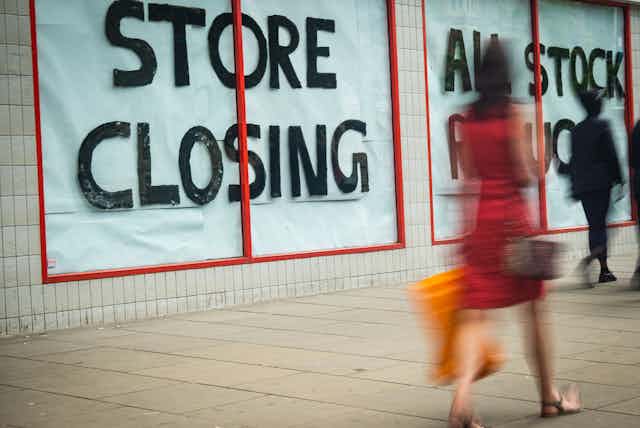 High Street 'Store Closing' sign with motion blurred shopper walking past