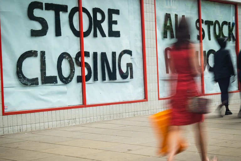 High Street 'Store Closing' sign with motion blurred shopper walking past