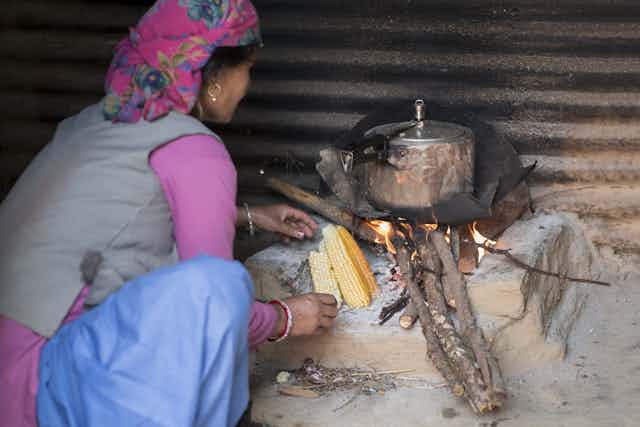 Woman cooking food on wood fire stove.