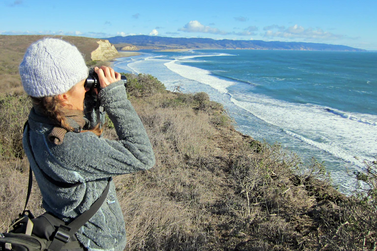 Woman with binoculars on seaside cliff