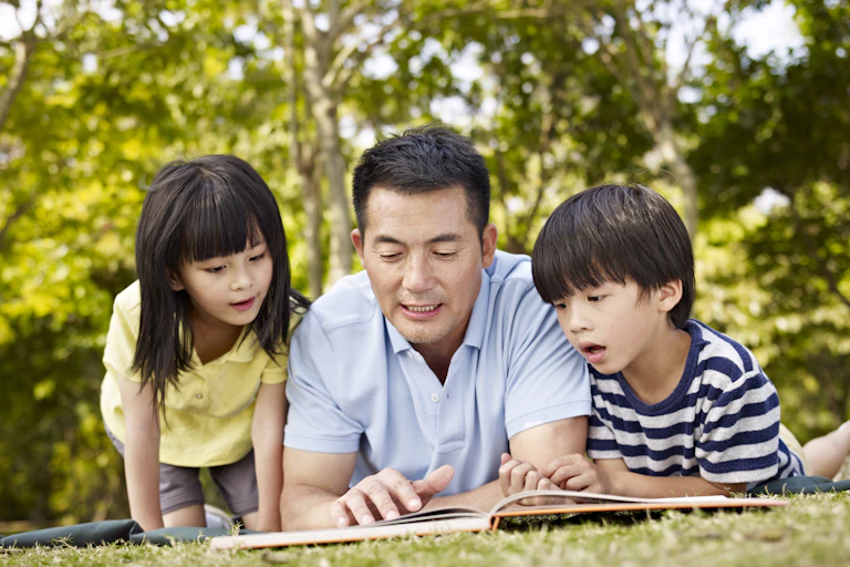 Family reading a picture book in the park.