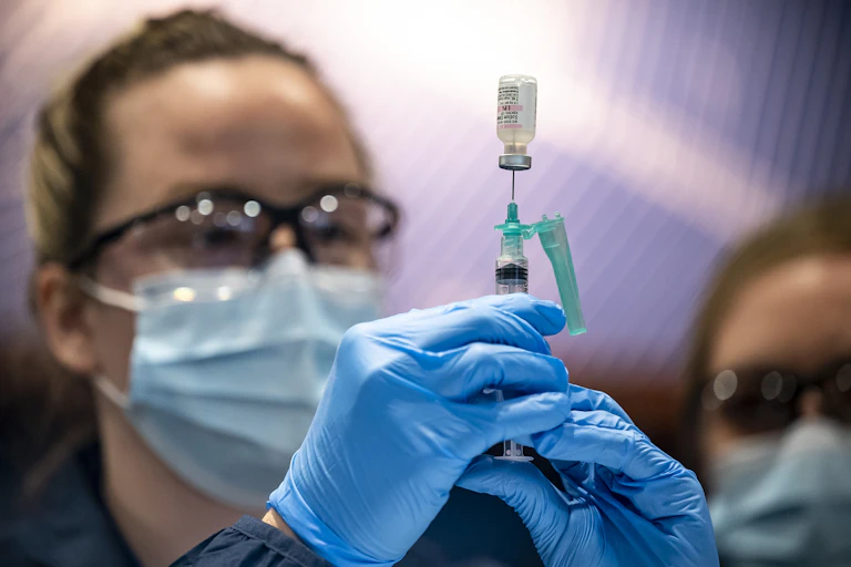 A vial and needle, in preparation to administer a vaccine