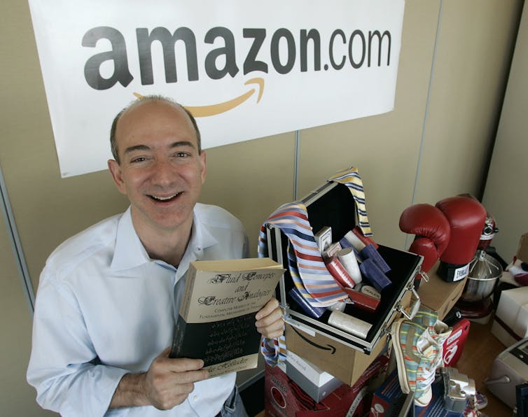 Jeff Bezos holding the first book he ever sold.