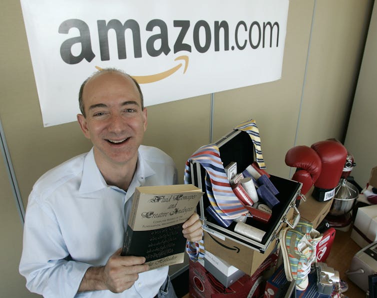 Jeff Bezos tient le premier livre qu'il ait jamais vendu.