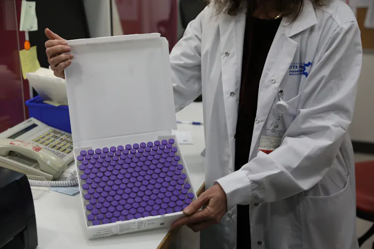 A health worker holding a case of Pfizer vaccine vials