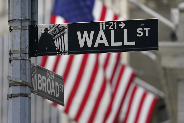 A Wall Street street sign with the American flag in the background.