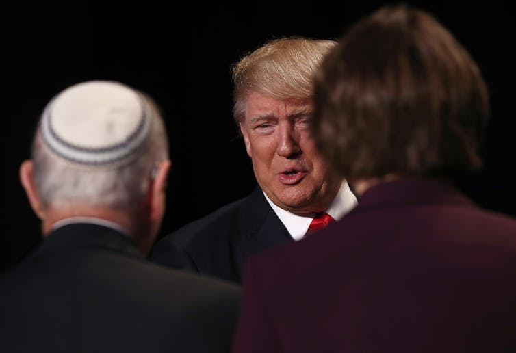 Donald Trump speaks to a man wearing a yarmulke who is turned away from the camera.