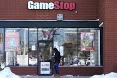 A customer checks on his cellphone as he walks to a GameStop store.