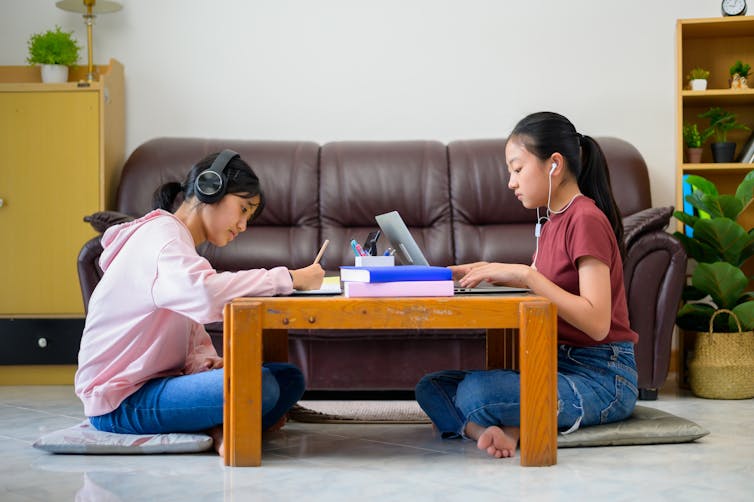 Two girls study at a coffee table.