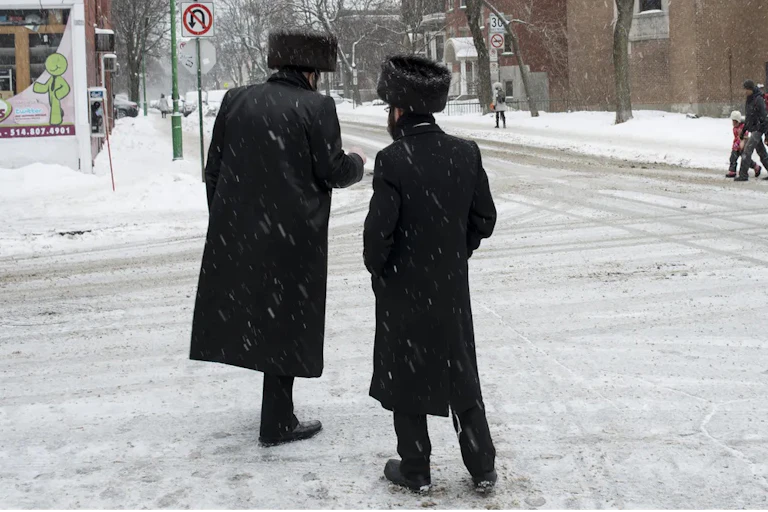 Two Hasidic men converse on a street.