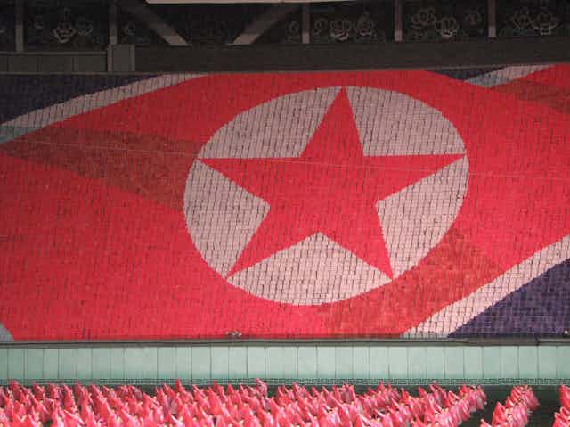 the North Korean flag formed by people in a stadium holding colored cards