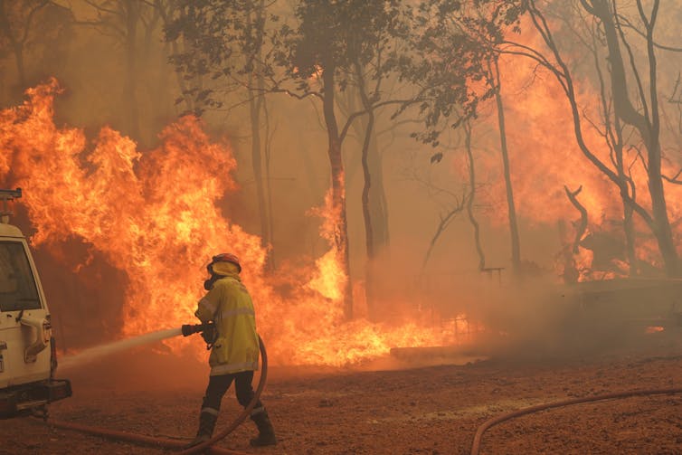 A firefighter battles a blaze with a hose