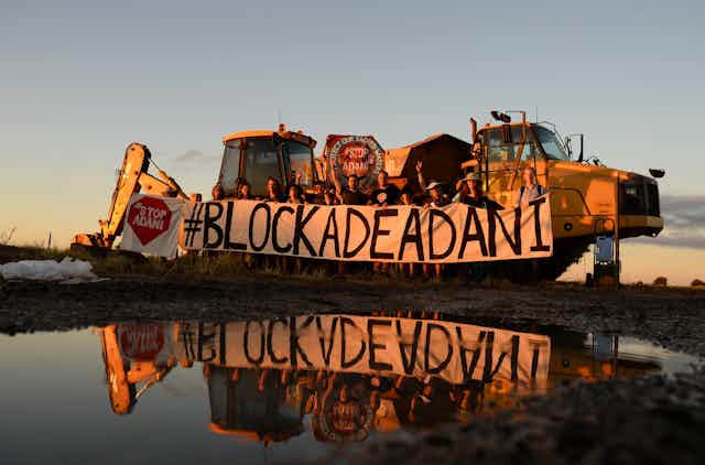 A protest group holds a sign 'Blockade Adani' 